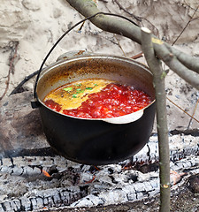 Image showing Soup cooking in sooty cauldron on campfire 