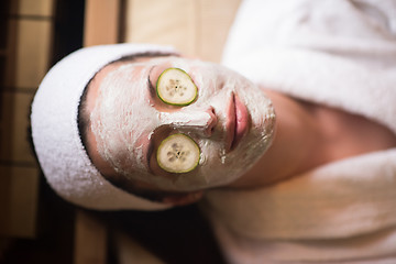 Image showing woman is getting facial clay mask at spa