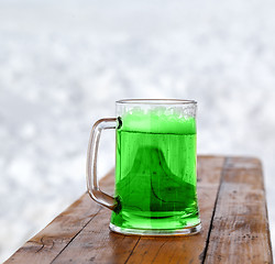 Image showing Full fresh cold glass of green beer on wooden bench