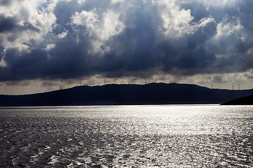 Image showing Sunlight sea, wind farm on mountains and cloudy sky before storm