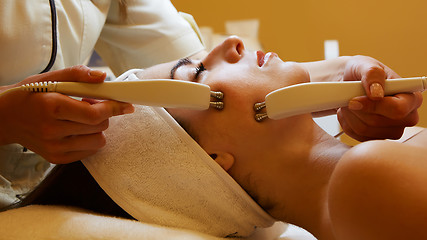 Image showing Cosmetology. Beautiful Woman At Spa Clinic Receiving Stimulating Electric Facial Treatment From Therapist. Closeup Of Young Female Face During Microcurrent Therapy. Beauty Treatment.