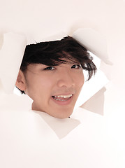 Image showing Asian man looking trough hole in paper.