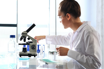 Image showing Chemist examine the sample under a microscope.