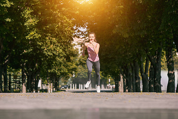 Image showing Pretty sporty woman jogging at park in sunrise light