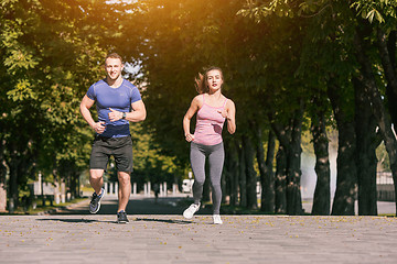 Image showing The sporty woman and man jogging at park in sunrise light