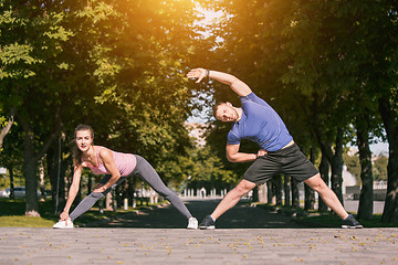 Image showing Fit fitness woman and man doing stretching exercises outdoors at park