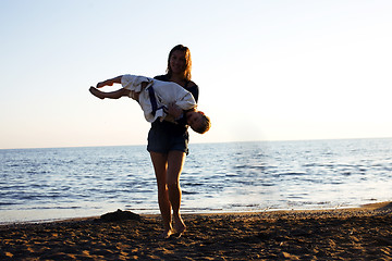 Image showing young mother with son resting on sea coast, happy family togethe