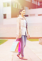 Image showing smiling woman with shopping bags coming from sale