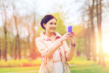 Image showing smiling woman taking picture with smartphone