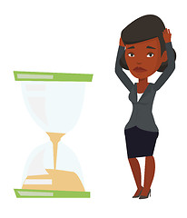 Image showing Desperate businesswoman looking at hourglass.