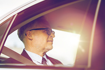 Image showing senior businessman driving on car back seat