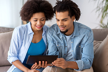 Image showing happy couple with tablet pc and earphones at home