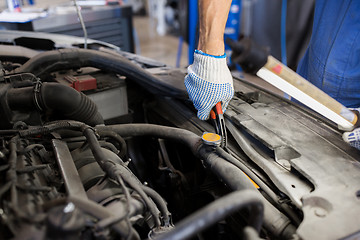 Image showing mechanic man with pliers repairing car at workshop