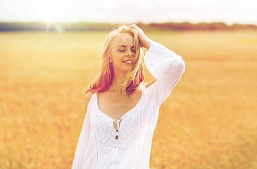 Image showing smiling young woman in white dress on cereal field