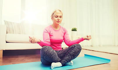 Image showing happy woman stretching leg on mat at home