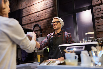 Image showing seller giving coffee cup to woman customer at cafe