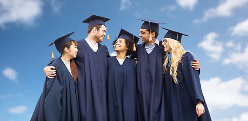Image showing happy students or bachelors over blue sky
