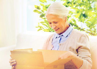 Image showing happy senior woman with parcel box at home