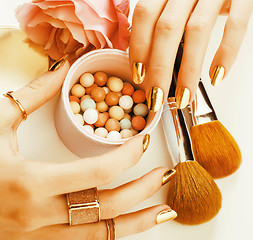 Image showing woman hands with golden manicure and many rings holding brushes,