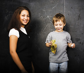 Image showing little cute boy with young teacher in classroom studying at blac