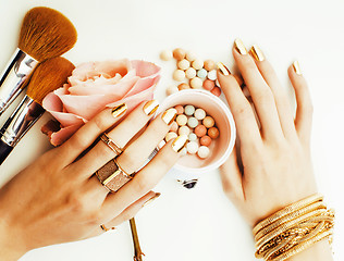 Image showing woman hands with golden manicure and many rings holding brushes,