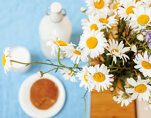 Image showing Simply stylish wooden kitchen with bottle of milk and glass on table, summer flowers camomile, healthy foog moring concept