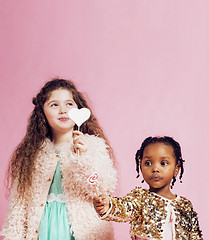 Image showing lifestyle people concept: diverse nation children playing together, caucasian boy with african little girl holding candy happy smiling 