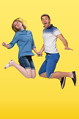 Image showing Portrait of a young couple jumping against yellow background