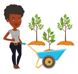 Image showing Woman pushing wheelbarrow with plant.