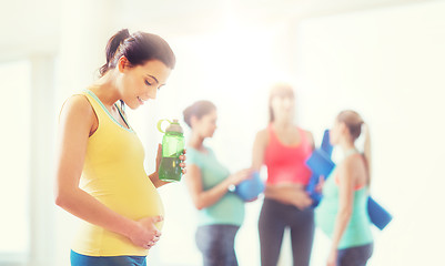 Image showing happy pregnant woman with water bottle in gym
