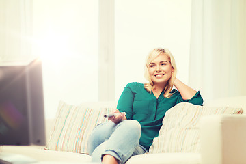 Image showing smiling woman with remote watching tv at home