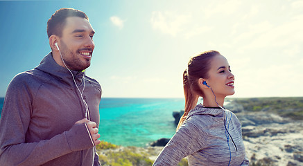 Image showing happy couple with earphones running in city