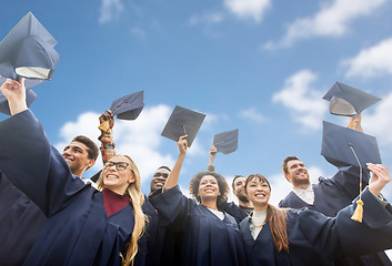 Image showing happy bachelors waving mortar boards over sky
