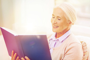 Image showing happy smiling senior woman reading book at home