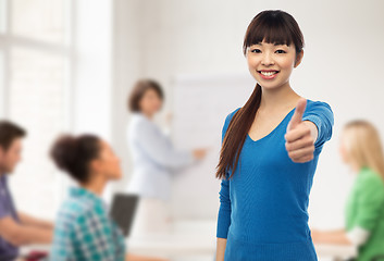 Image showing happy smiling young woman showing thumbs up