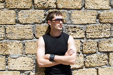Image showing Young man in sunglasses standing near a wall 1