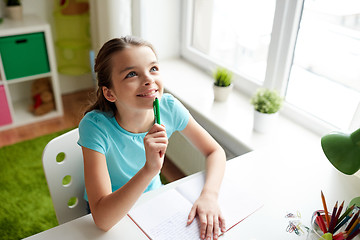 Image showing happy girl with notebook dreaming at home