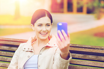 Image showing smiling woman taking picture with smartphone