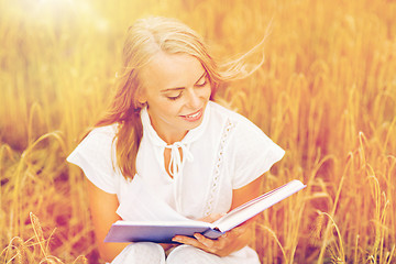 Image showing smiling young woman reading book on cereal field