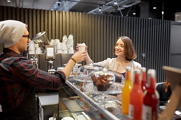 Image showing seller giving coffee cup to woman customer at cafe