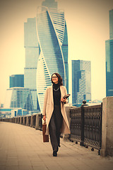 Image showing Smiling beautiful woman in a light coat against the backdrop of 