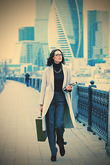 Image showing Beautiful woman in a light coat with a wooden case