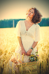 Image showing beautiful smiling woman in a white dress standing among the ears