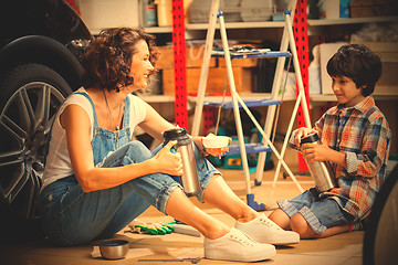 Image showing Beautiful woman and boy in the garage near the car