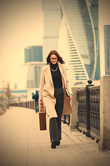 Image showing Smiling dark-haired woman in a bright coat is on the waterfront