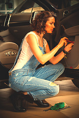 Image showing Woman car mechanic in blue overalls adjusts the car door