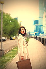 Image showing beautiful business woman in a light coat with a stylish wooden c