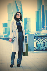 Image showing Beautiful smiling woman in a light trendy coat on the waterfront