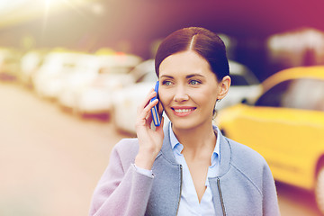 Image showing smiling woman with smartphone over taxi in city