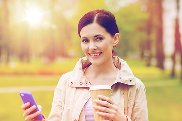 Image showing smiling woman with smartphone and coffee in park